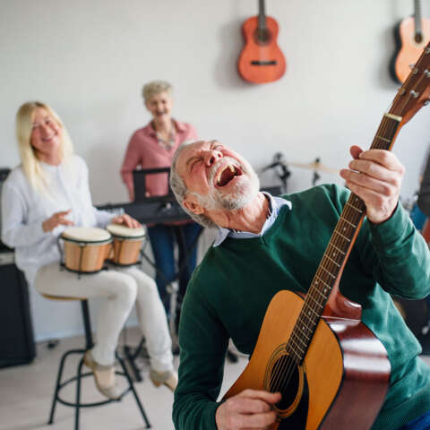 Old Man Jamming on a Guitar with Friends