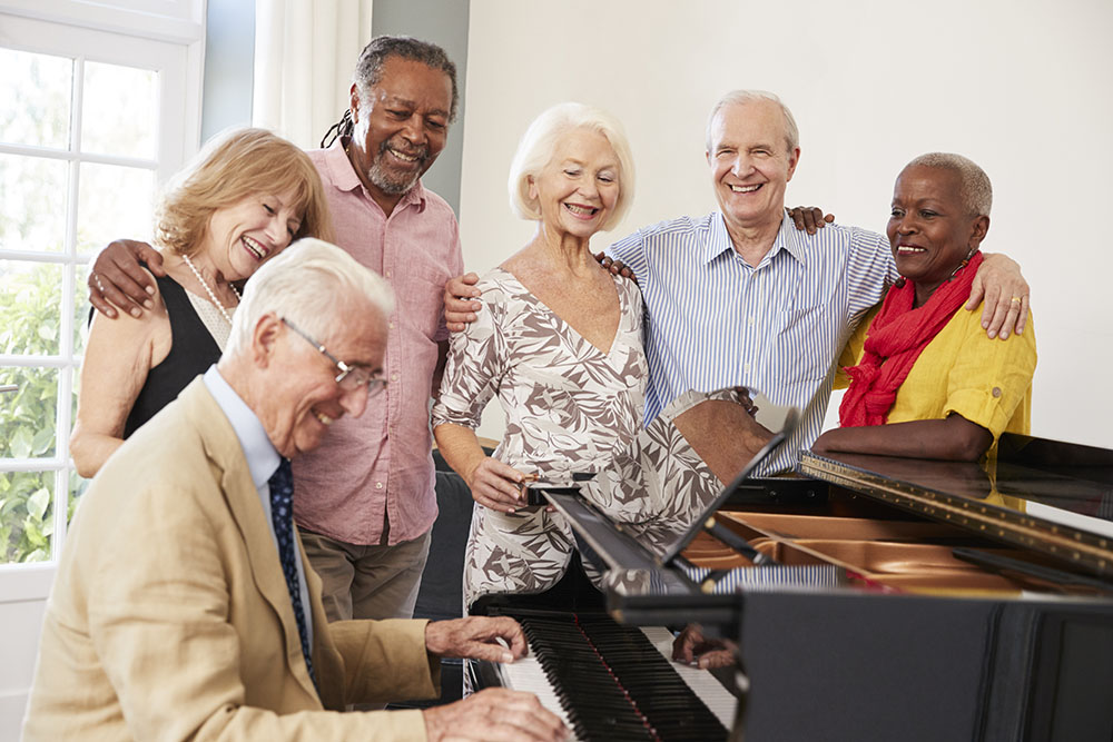 Group Of Seniors Standing By Piano And Singing Together